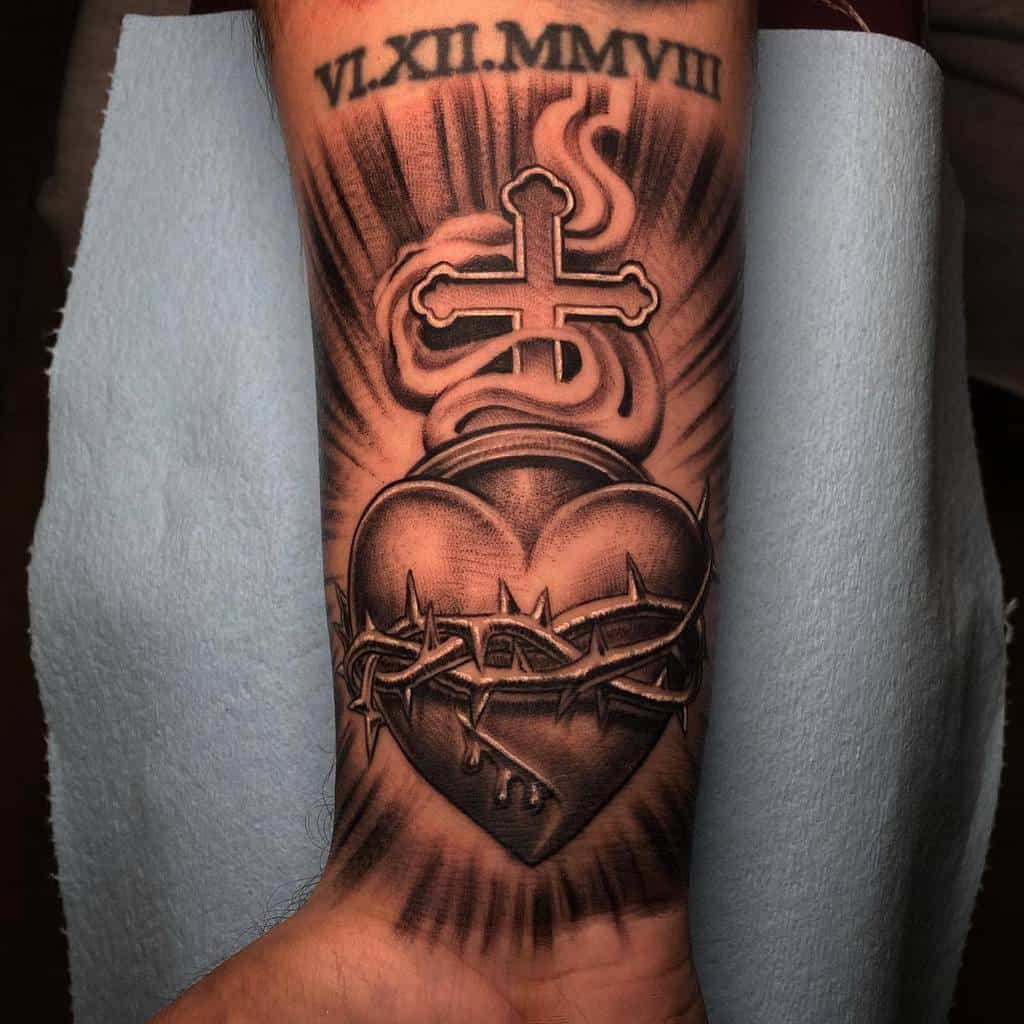 Tattoo of a bleeding heart wrapped in barbed wire, with a cross above and Roman numerals VL.XII.MMVIII on the arm