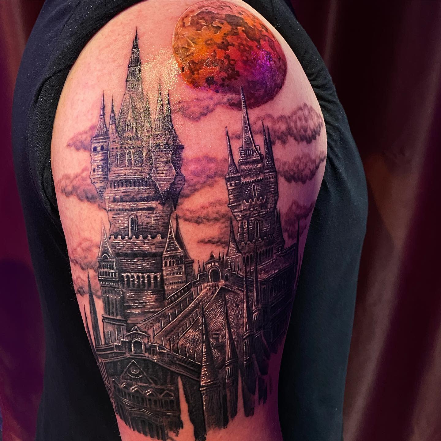Intricate tattoo of a gothic castle from Bloodborne with a vibrant blood moon on the shoulder
