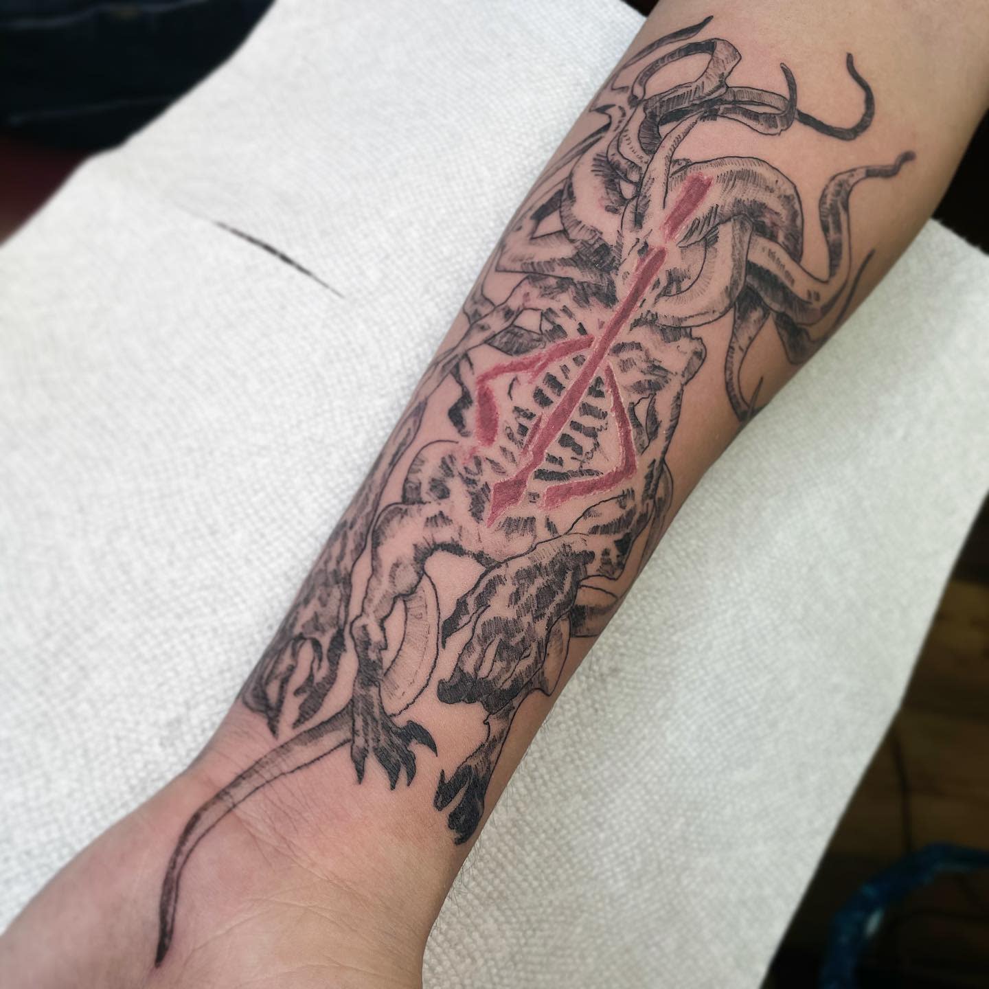 Forearm tattoo depicting a monstrous Bloodborne beast with intricate details and a red scar
