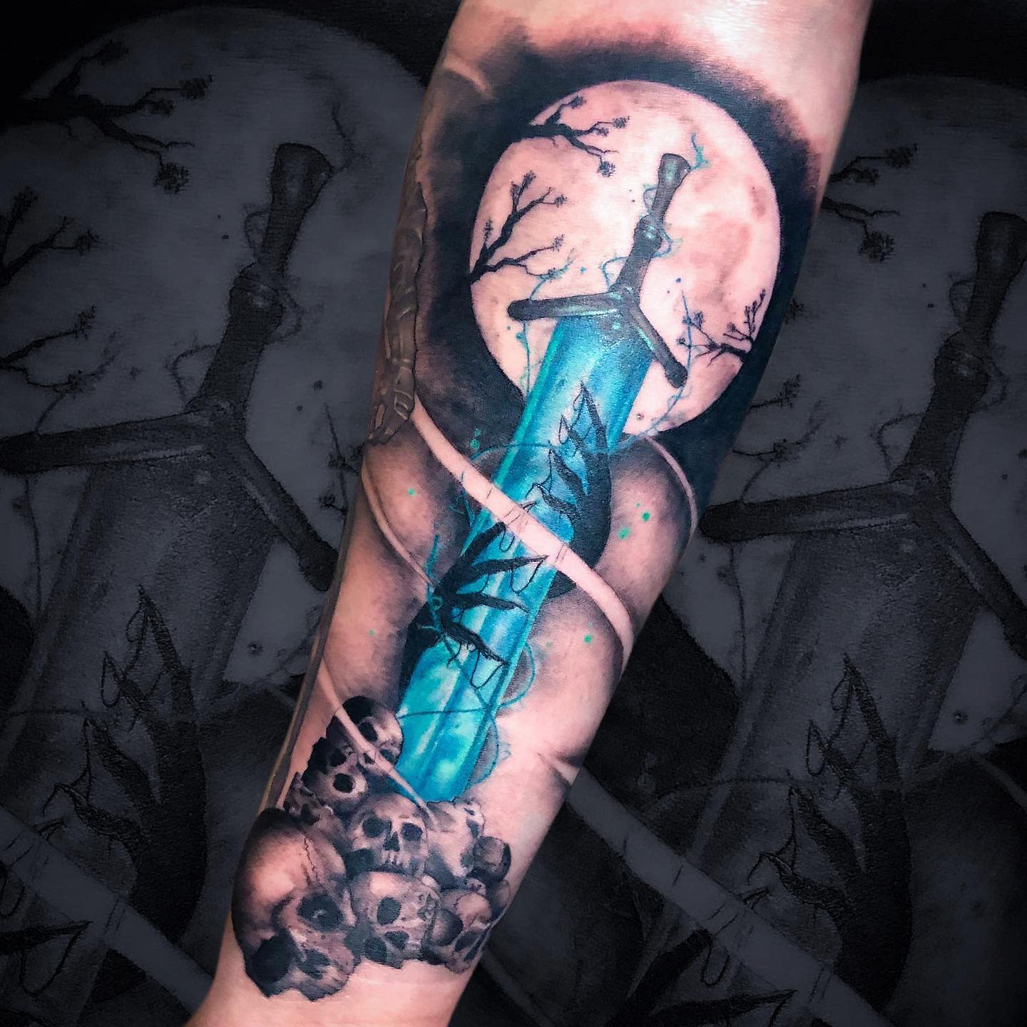 Forearm tattoo depicting the iconic Holy Moonlight Sword with a vibrant blue blade and skulls