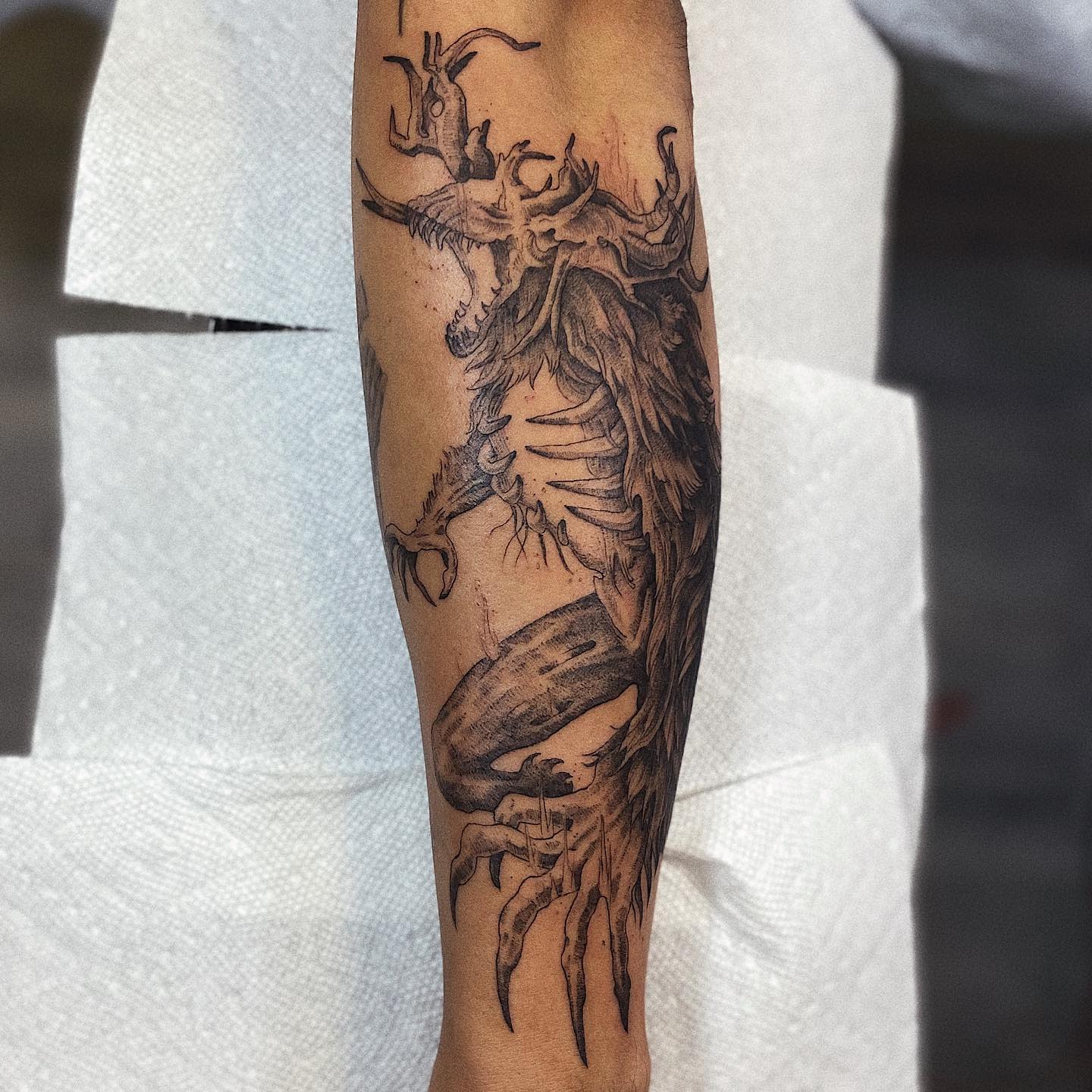 Forearm tattoo of a menacing Bloodborne beast with sharp claws and intricate skeletal details