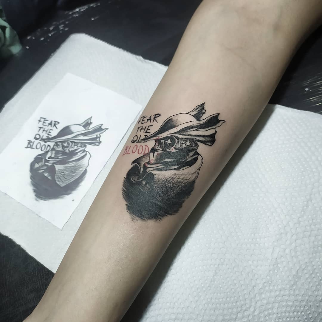 Minimalist Bloodborne tattoo featuring a hunter's profile with 'Fear the Old Blood' in black and red