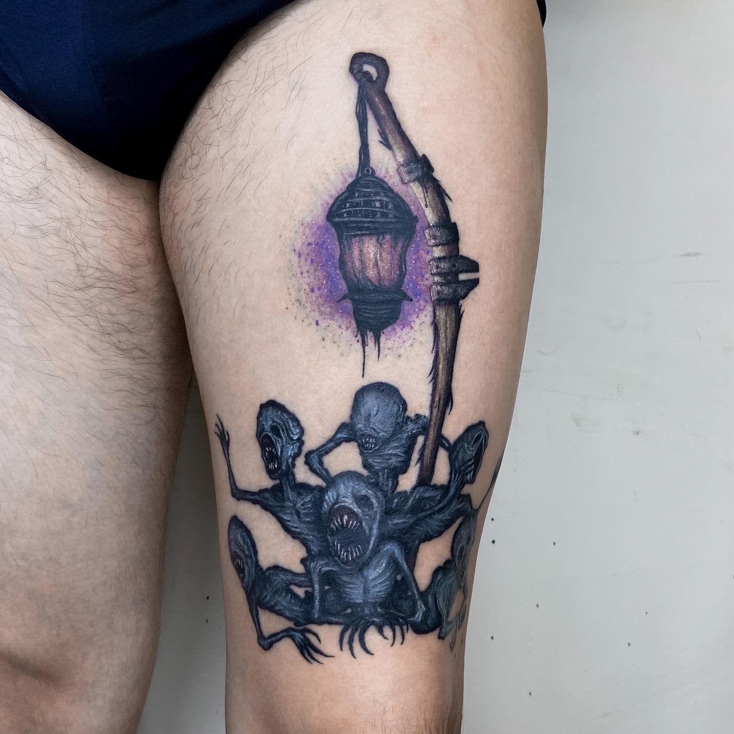 Thigh tattoo of Bloodborne's Messenger creatures gathered beneath a glowing lantern with a purple aura