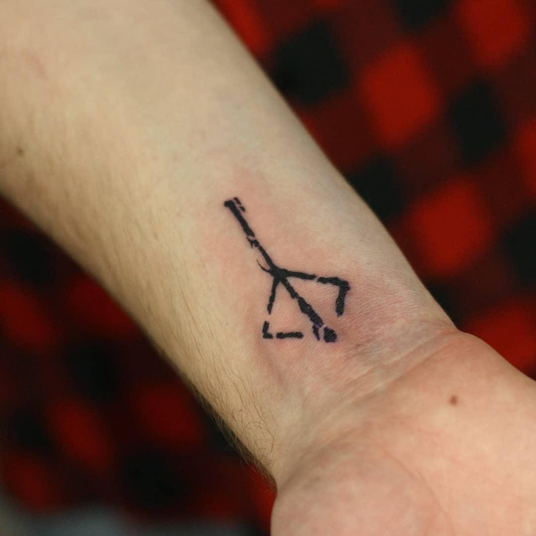 Small wrist tattoo of the Bloodborne hunter's mark in simple, black ink