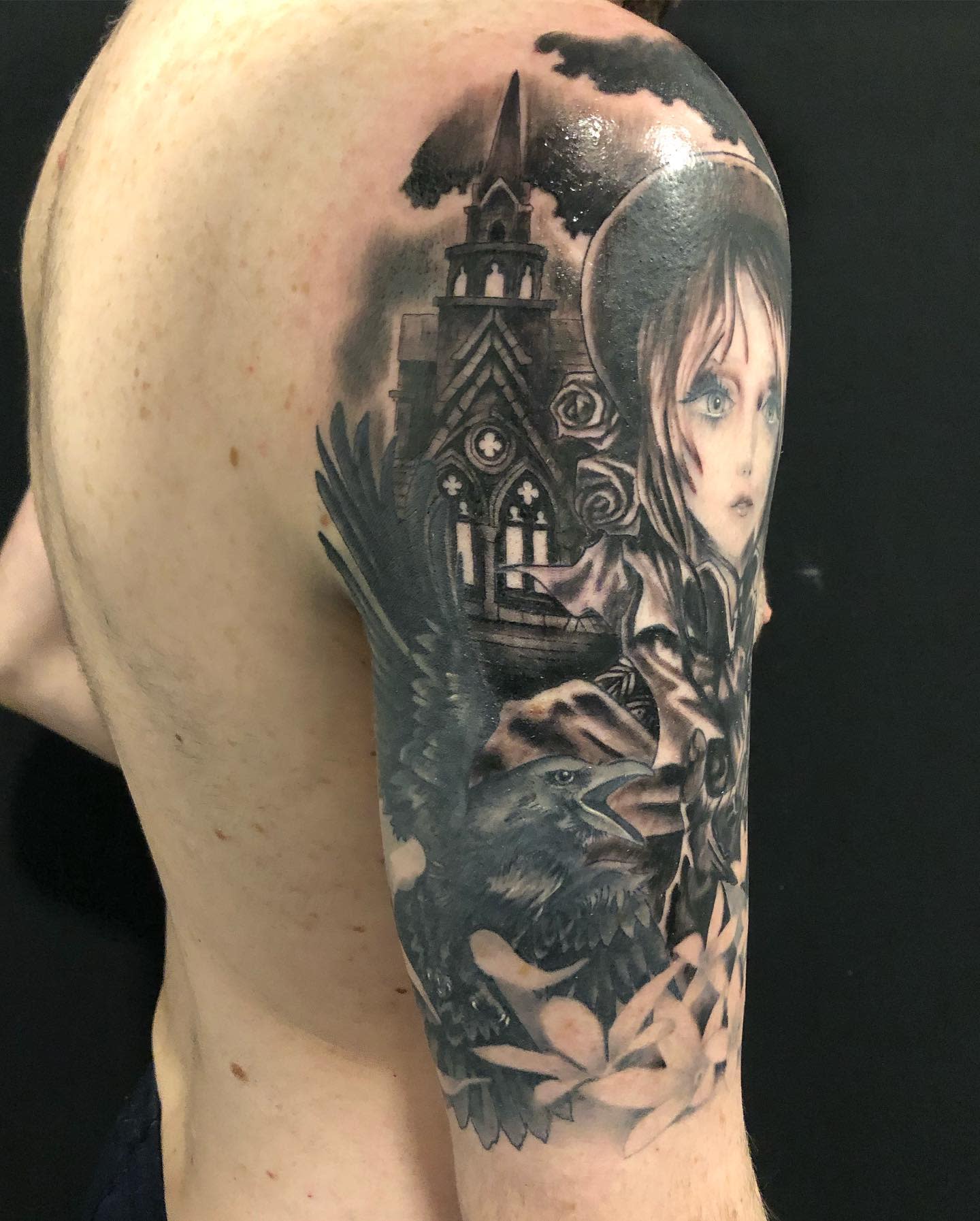 Upper arm tattoo featuring a gothic church, a crow, and a character from Bloodborne with detailed shading