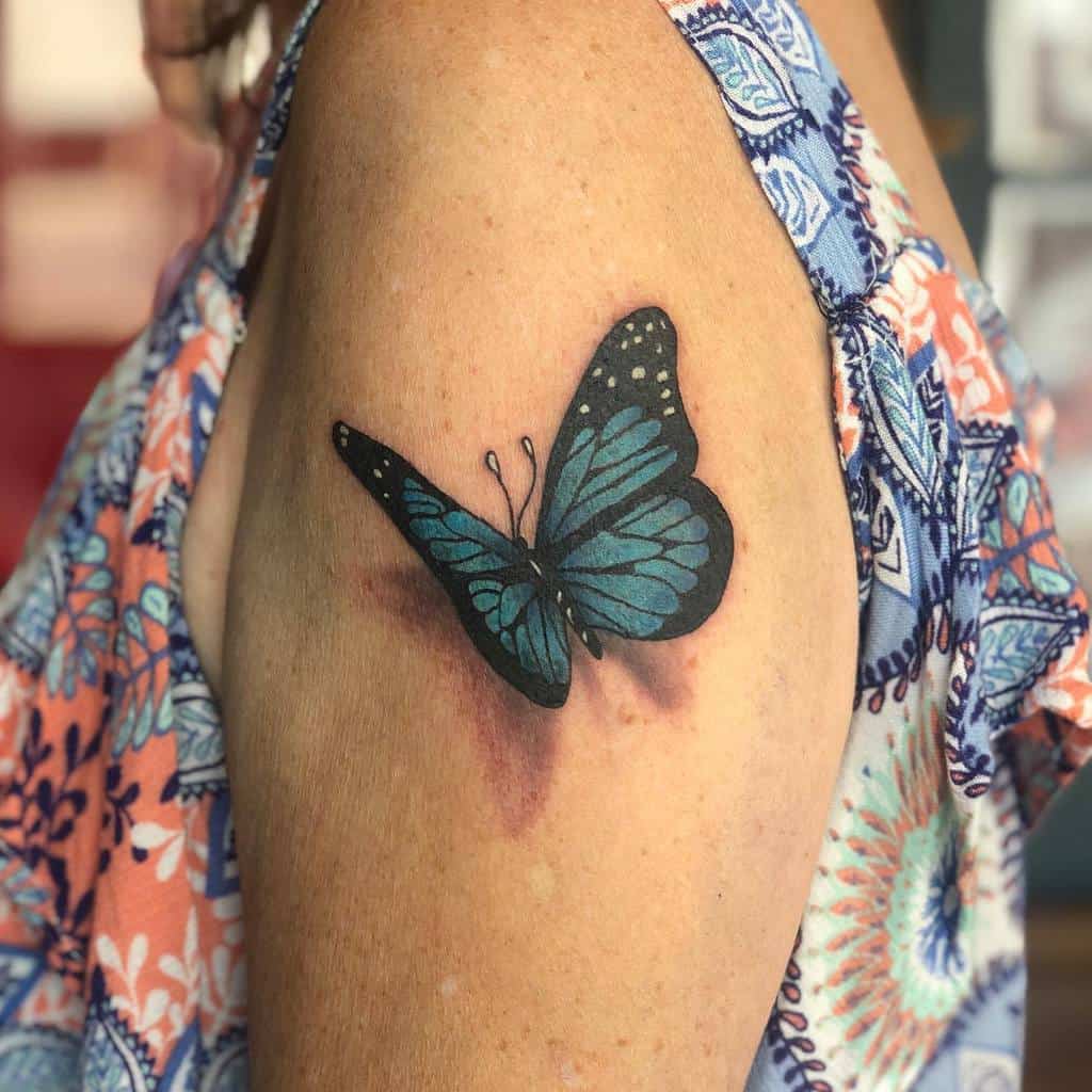 Blue and black butterfly tattoo on an upper arm