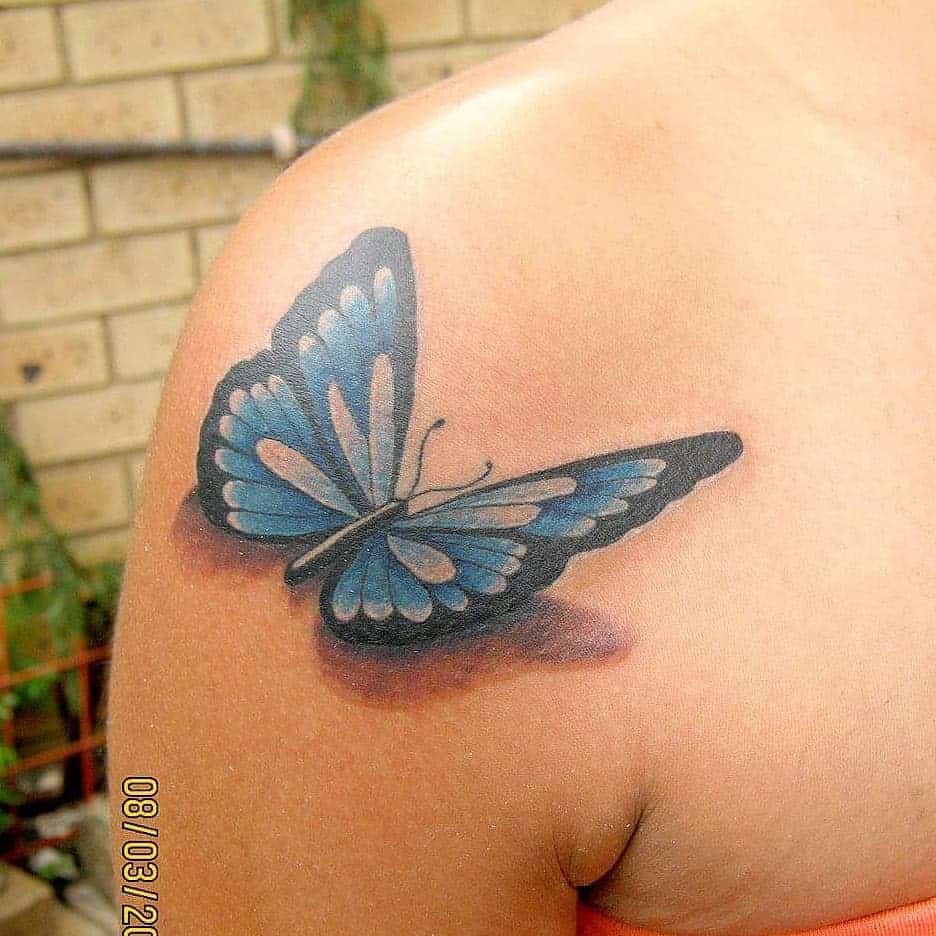 Tattoo of a blue butterfly with black accents on a person's shoulder