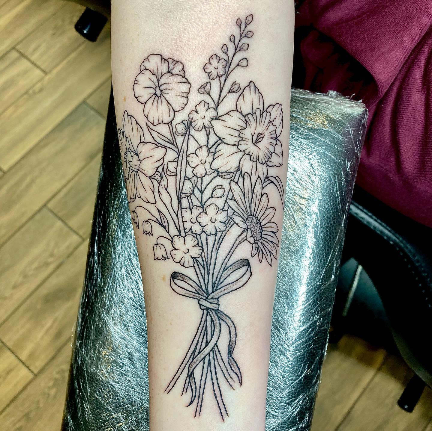 Black and gray floral tattoo of a bouquet on a forearm