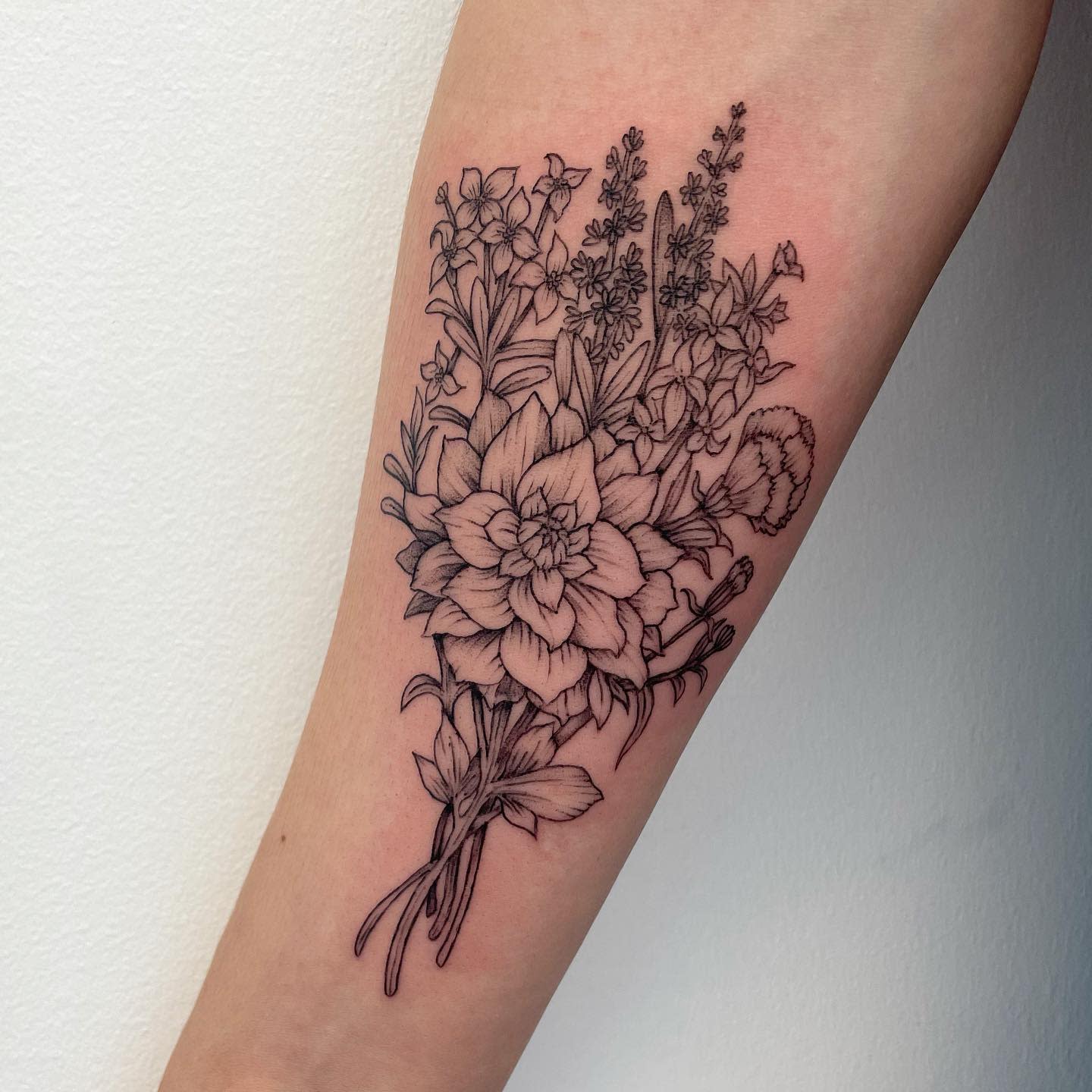 A detailed black and white floral tattoo on a forearm