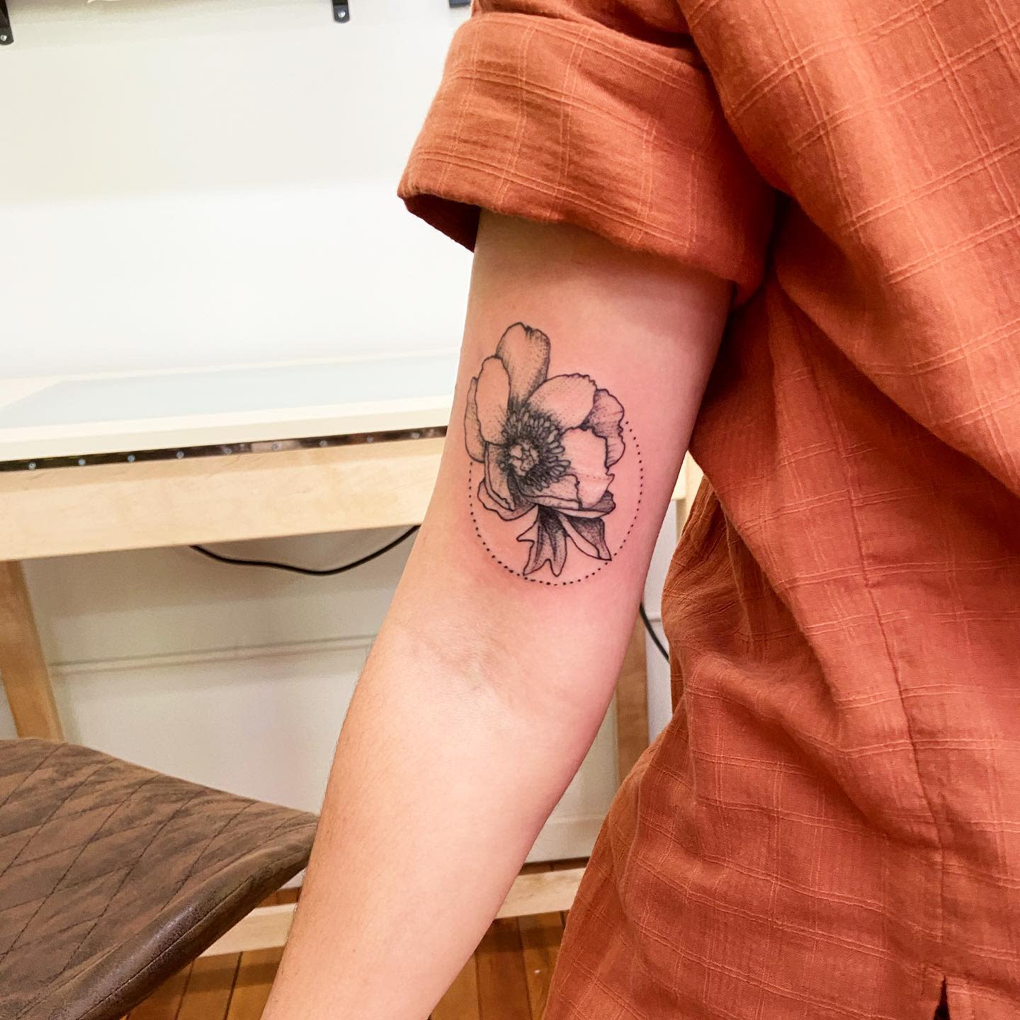 Individual showcasing a floral tattoo on their upper arm