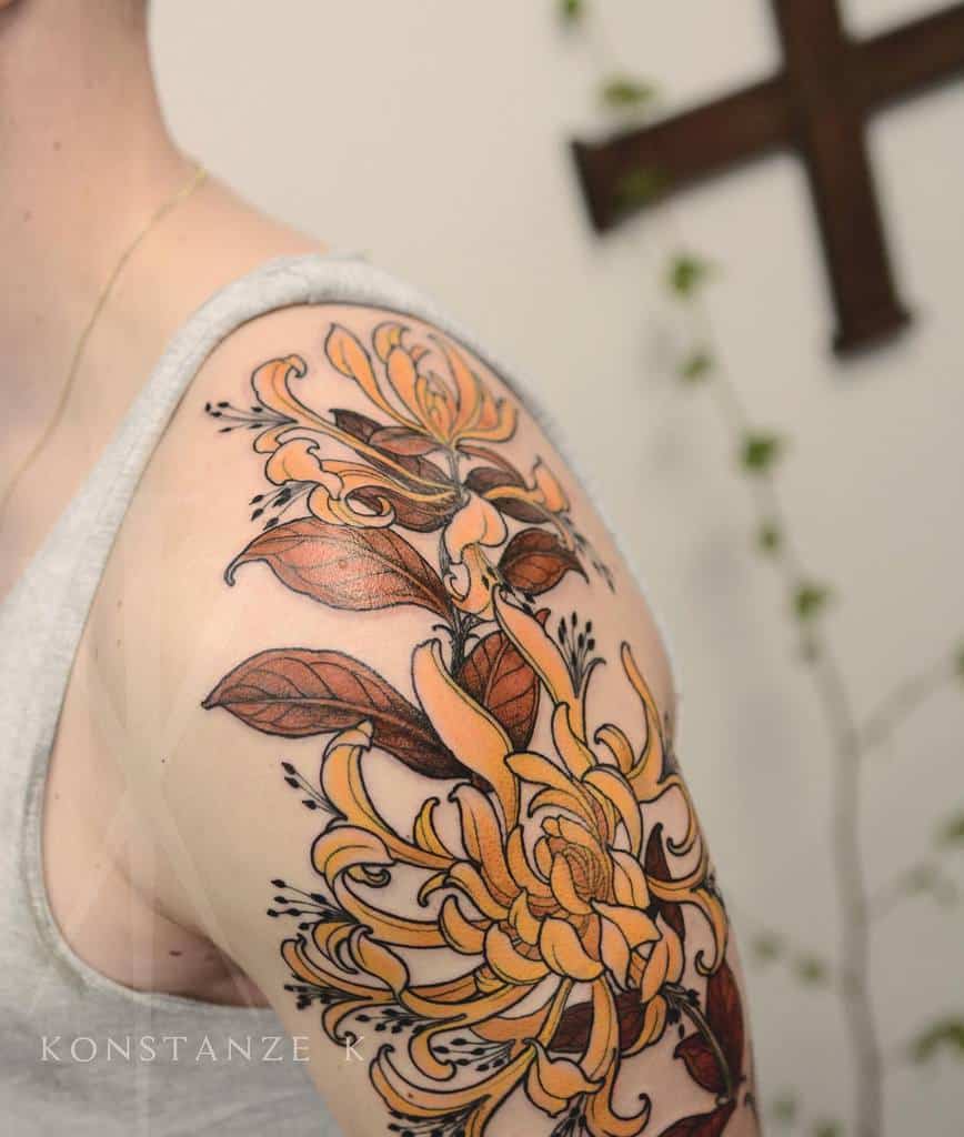 Dynamic floral tattoo on the shoulder, highlighting detailed yellow honeysuckle blooms and brown leaves