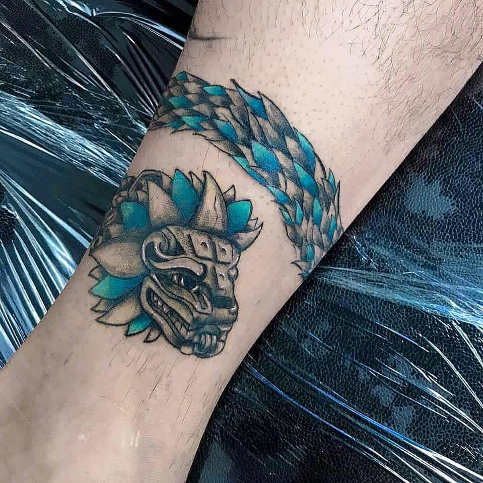Vibrant Quetzalcoatl tattoo with blue accents, showcasing the feathered serpent in detail