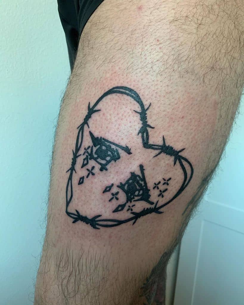 Tattoo of a black heart made from barbed wire with two eyes inside