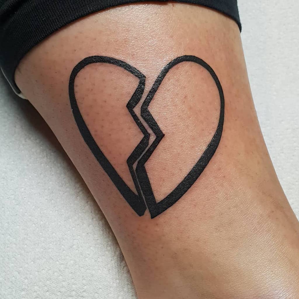 Bold black outline tattoo depicting a heart broken into two pieces, emphasizing clean lines and modern design