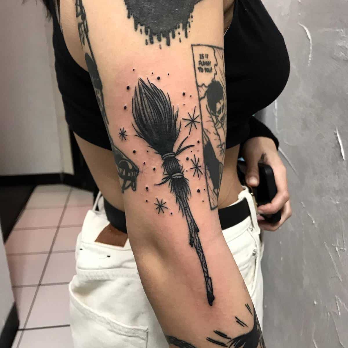 Detailed broomstick tattoo on upper arm