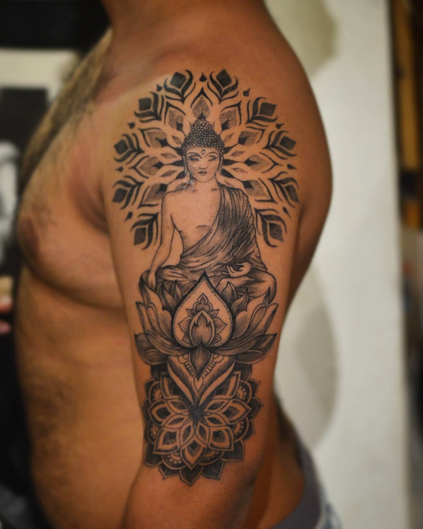 Tattoo of Buddha with lotus flower and mandala design on upper arm and shoulder