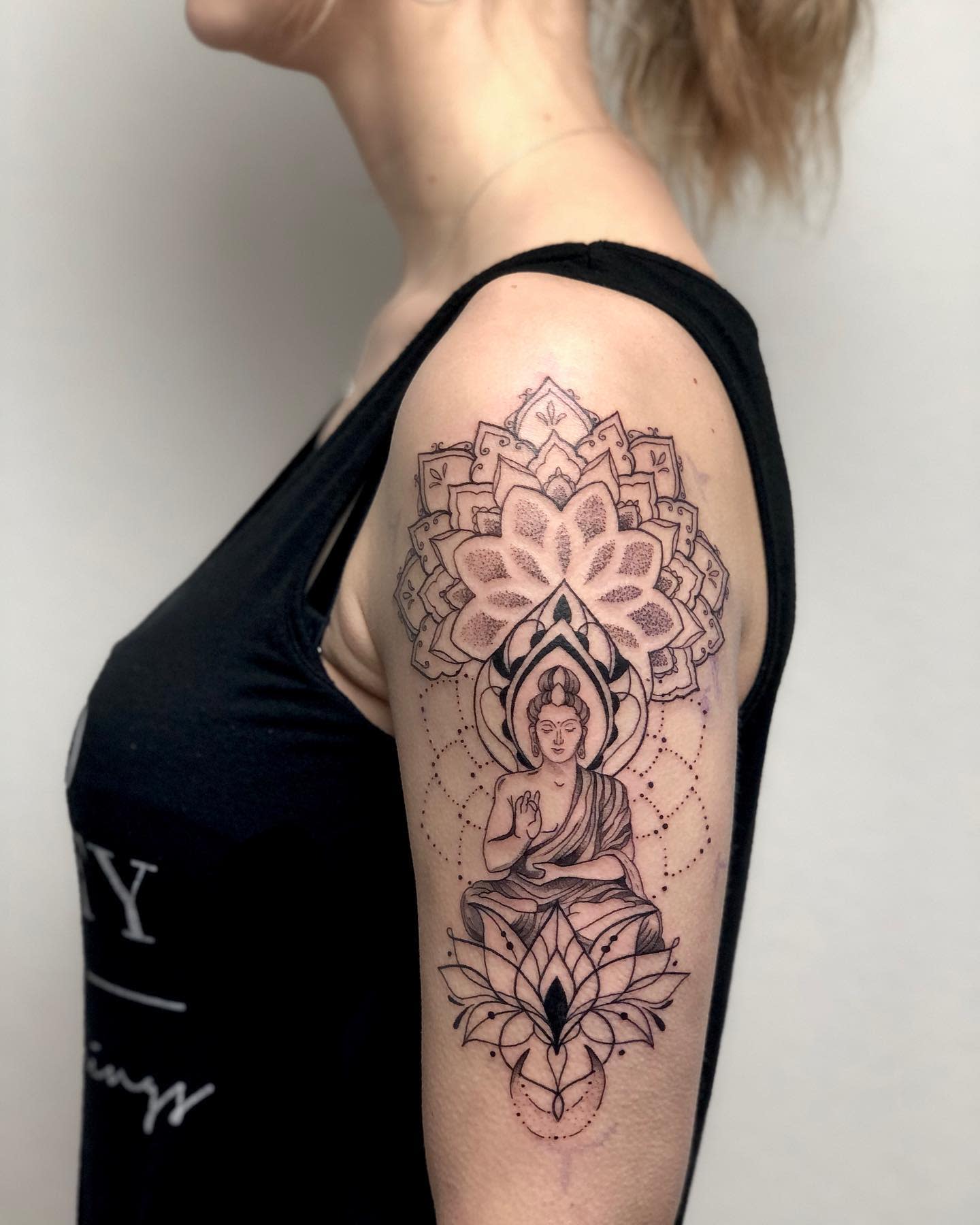 Side view showcasing an intricate Buddha tattoo on the upper arm and shoulder