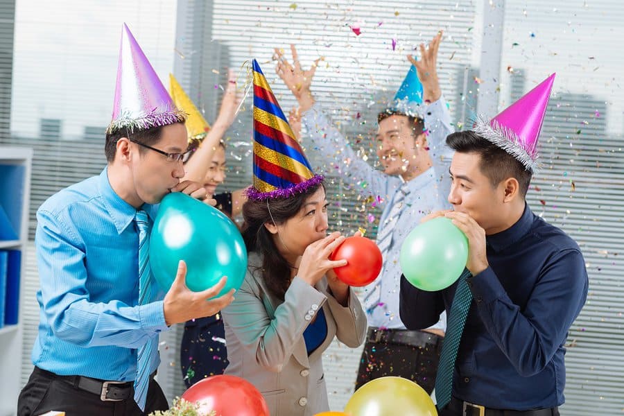 Business colleagues blowing up balloons at the office party