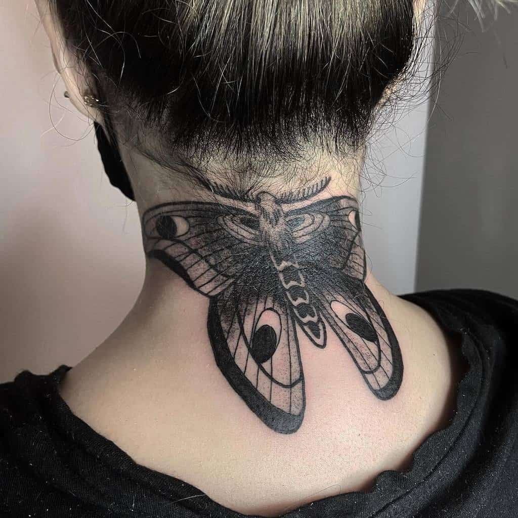 A detailed black moth tattoo expertly inked on the back of a neck, showcasing intricate patterns and shading