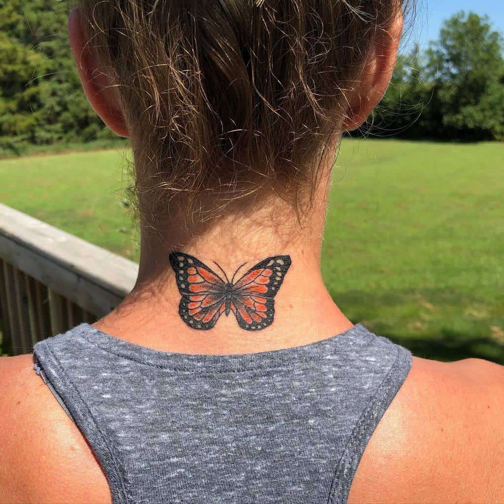 Monarch butterfly tattoo on the back of a woman's neck, detailed and sunlit