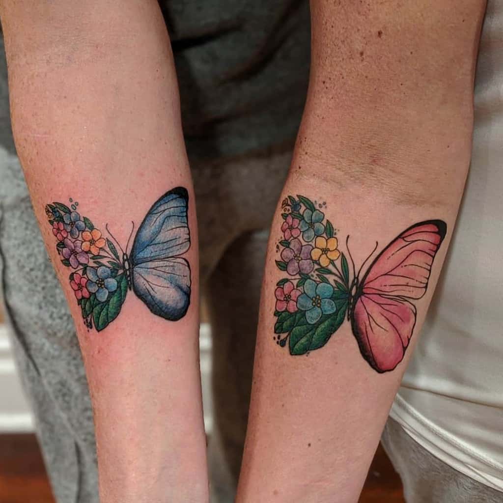 Matching butterfly tattoos on forearms, with one side blending into blue and the other into pink flowers, creating a vibrant, artistic design.