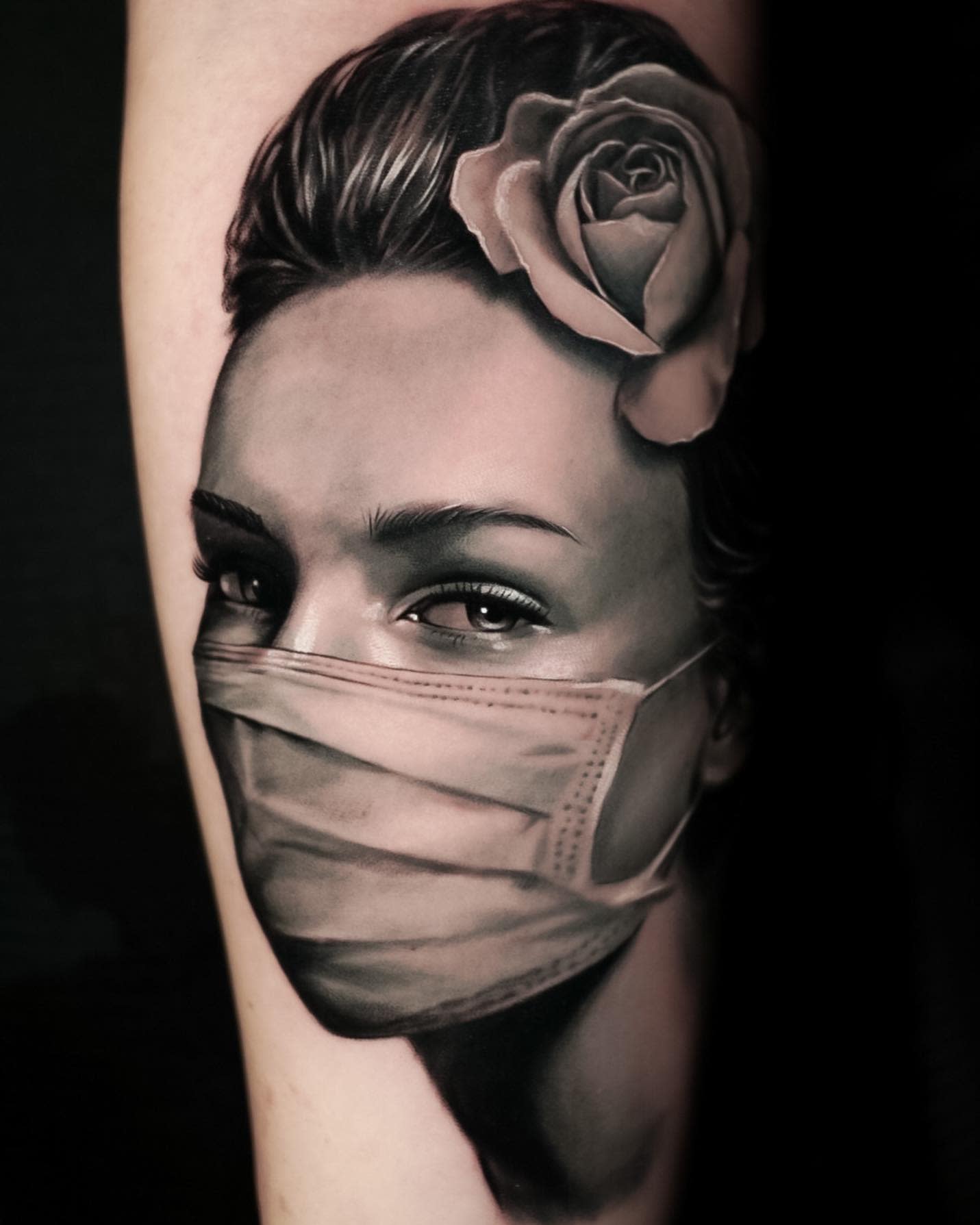Tattoo of a woman wearing a mask with a rose in her hair on a forearm