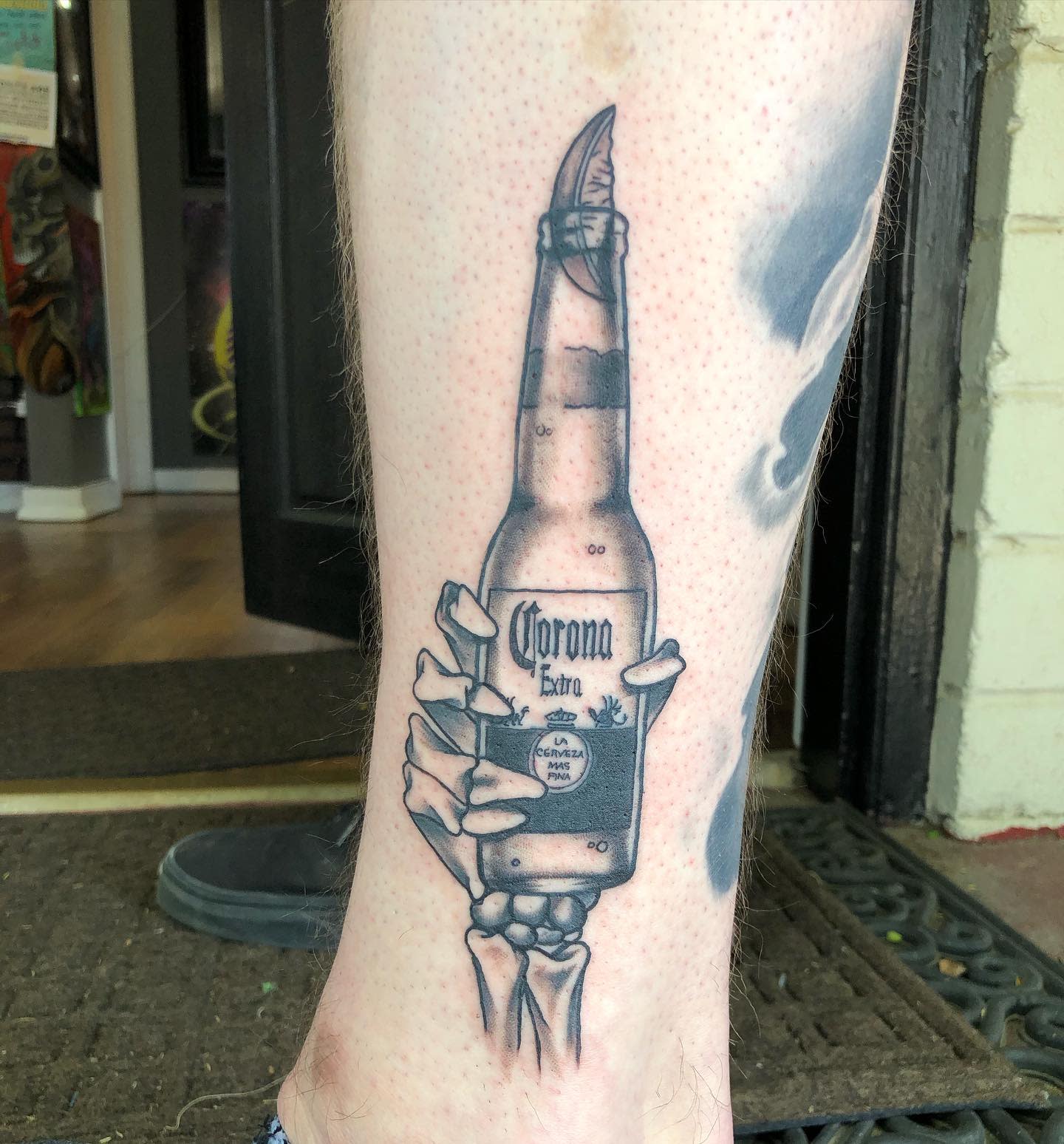 Tattoo of a skeleton hand holding a Corona beer bottle on a calf