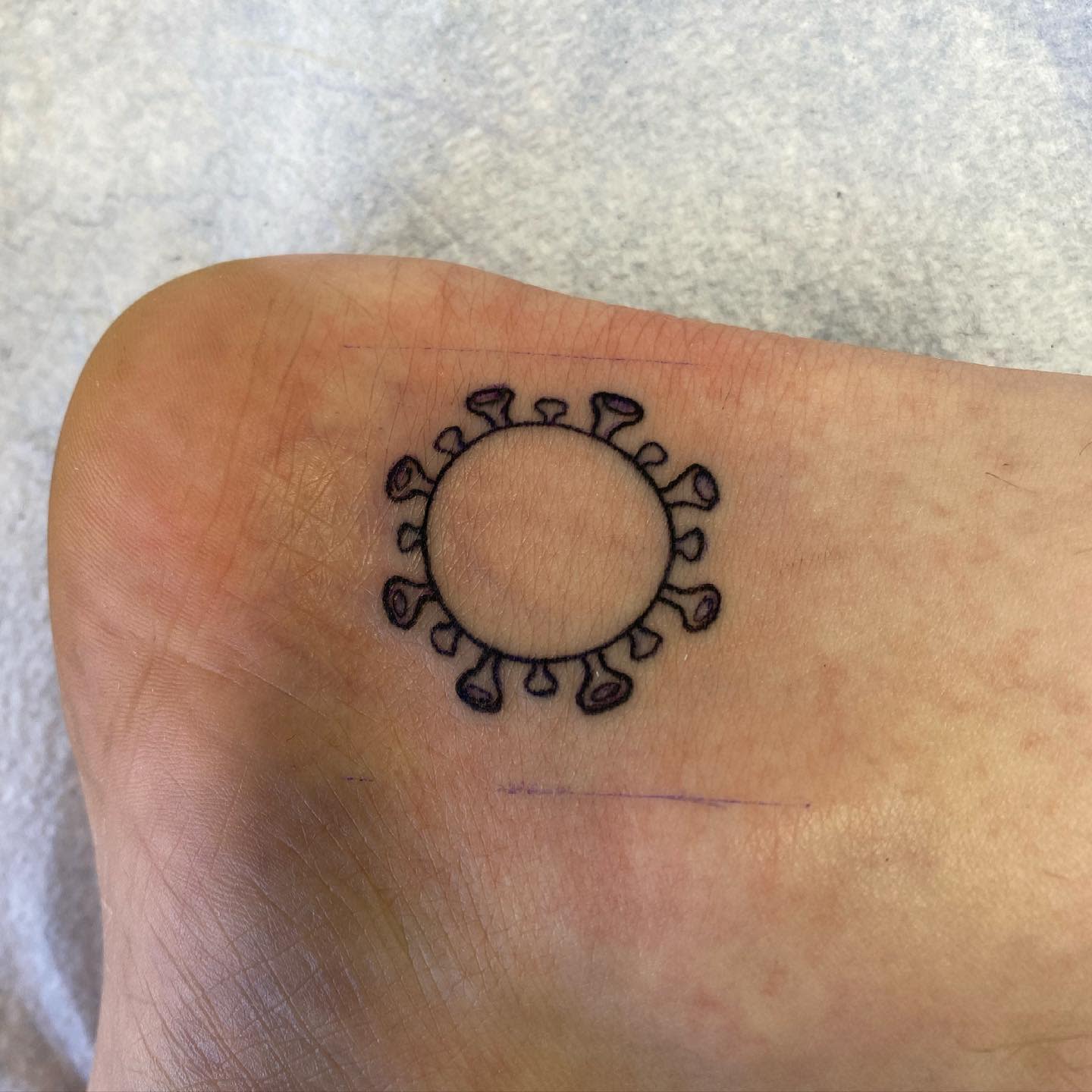 Simple tattoo of a virus-like shape on the skin resembling a typical depiction of a virus