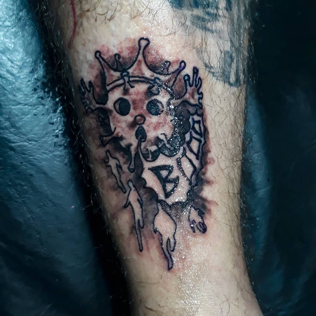 Tattoo of king's skull with crown and beard, and "Bite" text on lower leg