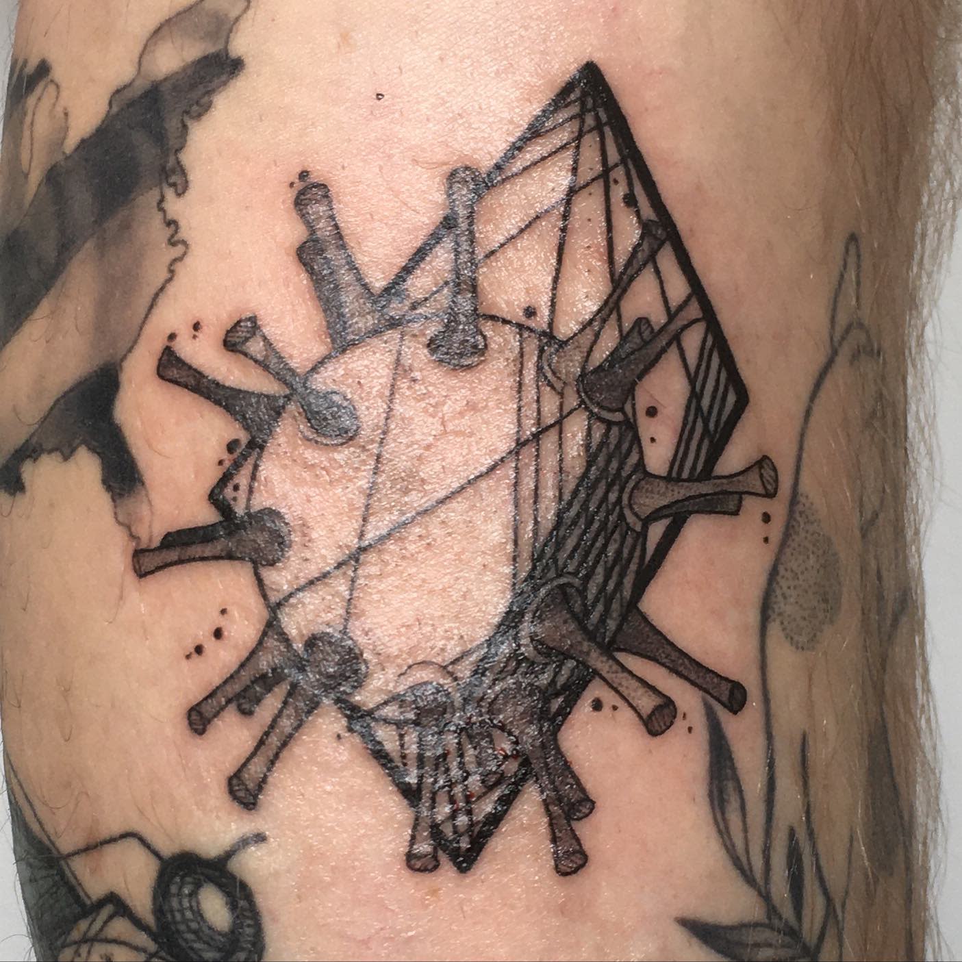 Tattoo of a geometrically stylized virus featuring spikes and intricate line patterns