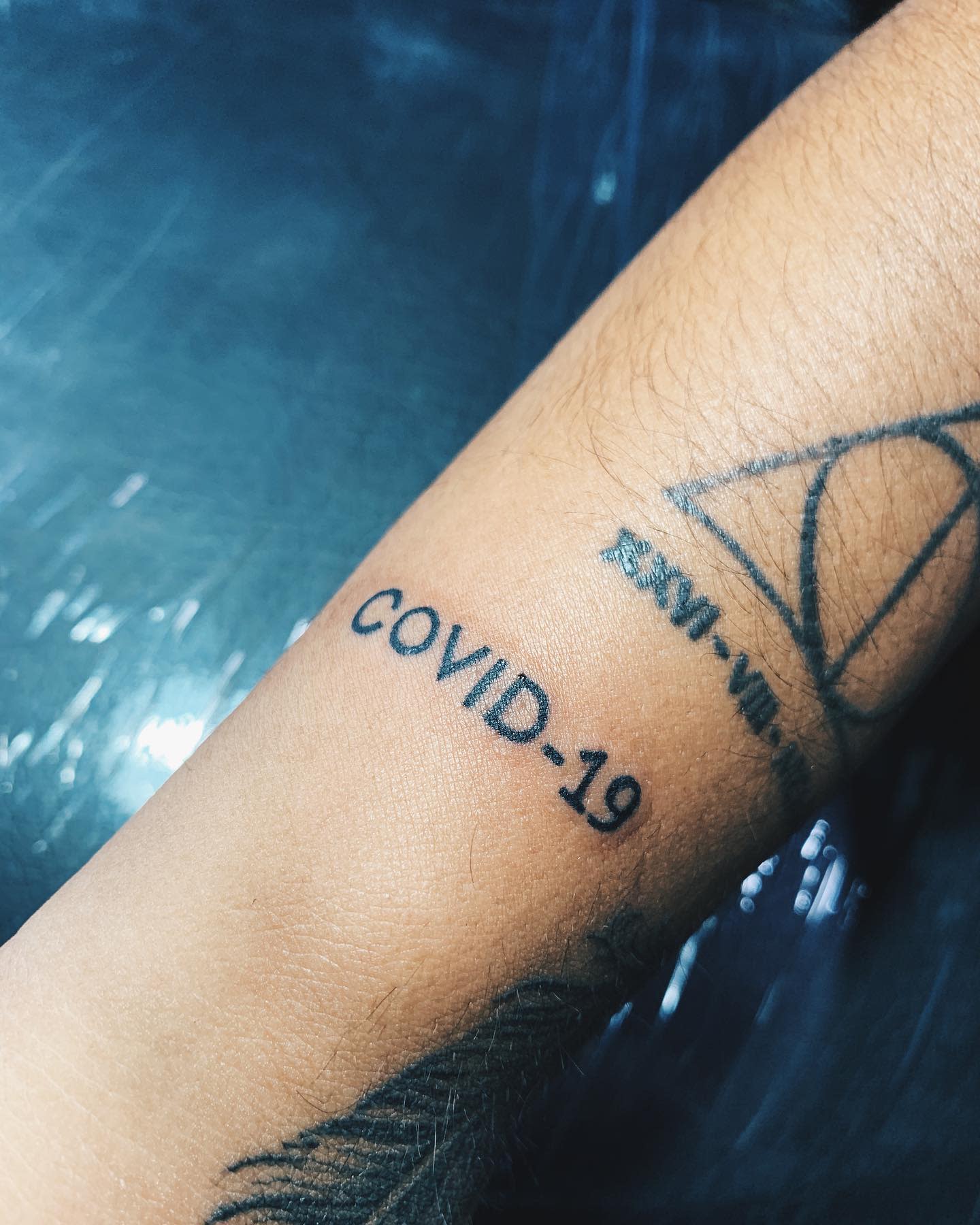 Close-up of a forearm with a "COVID-19" tattoo