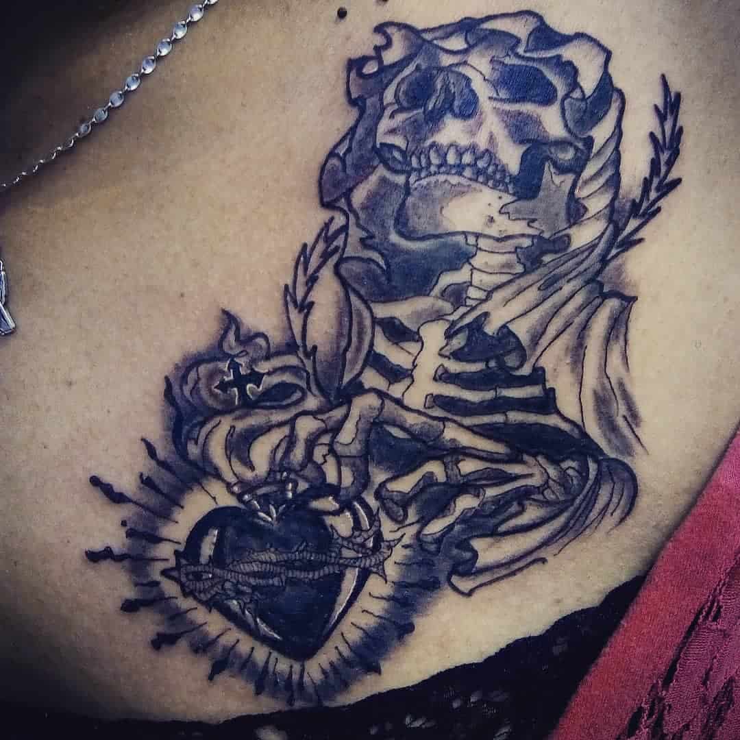Santa Muerte chest tattoo showing a skeleton holding a flaming sacred heart with radiant lines