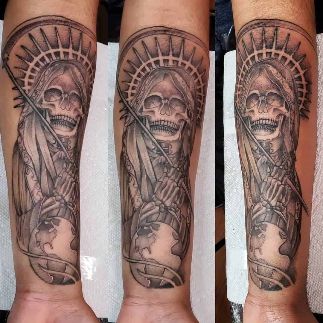Santa Muerte forearm tattoo with a halo, skeletal face, and her hands gripping a scythe