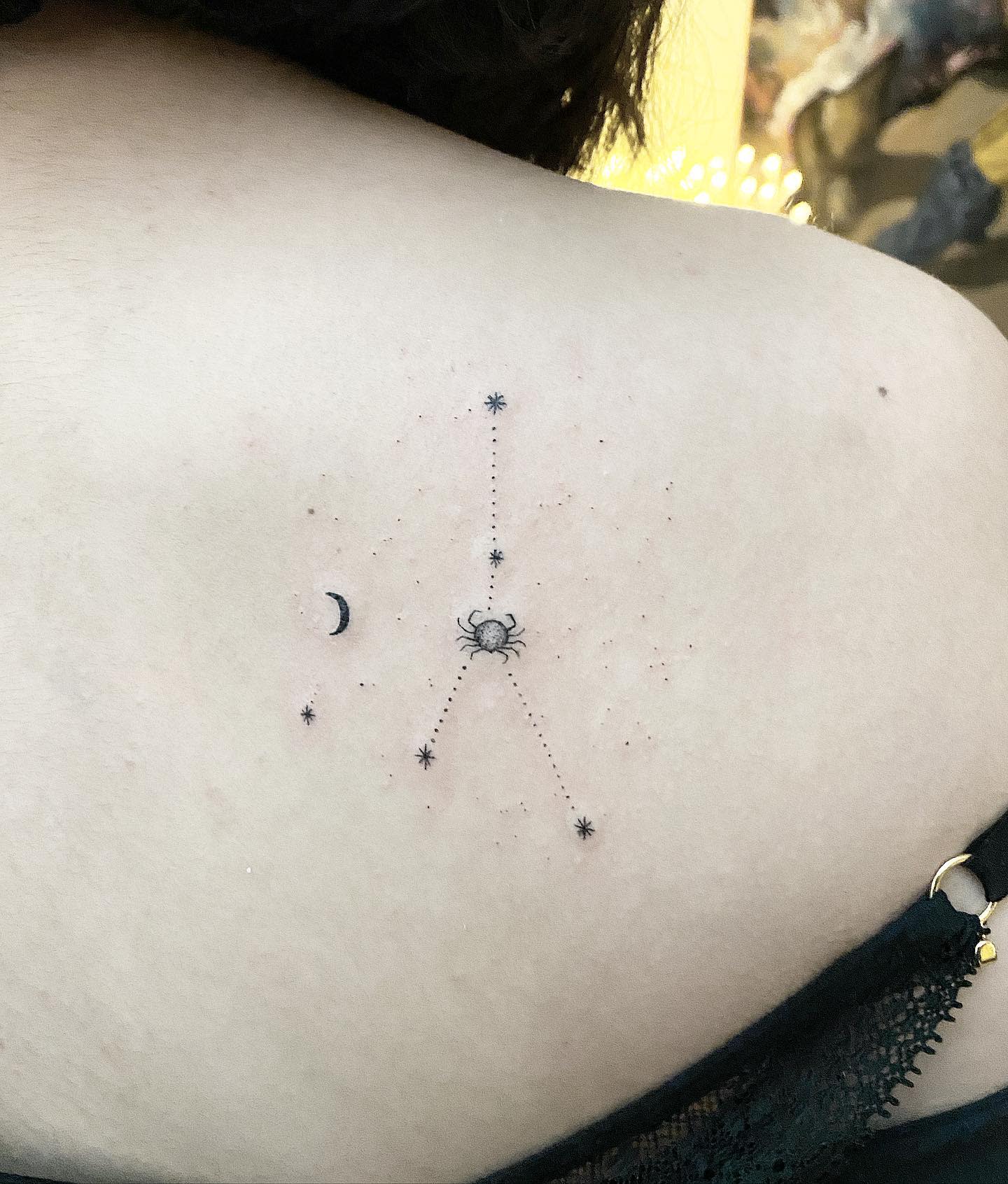 Minimalist constellation tattoo with a cancer, crescent moon, and stars on their back