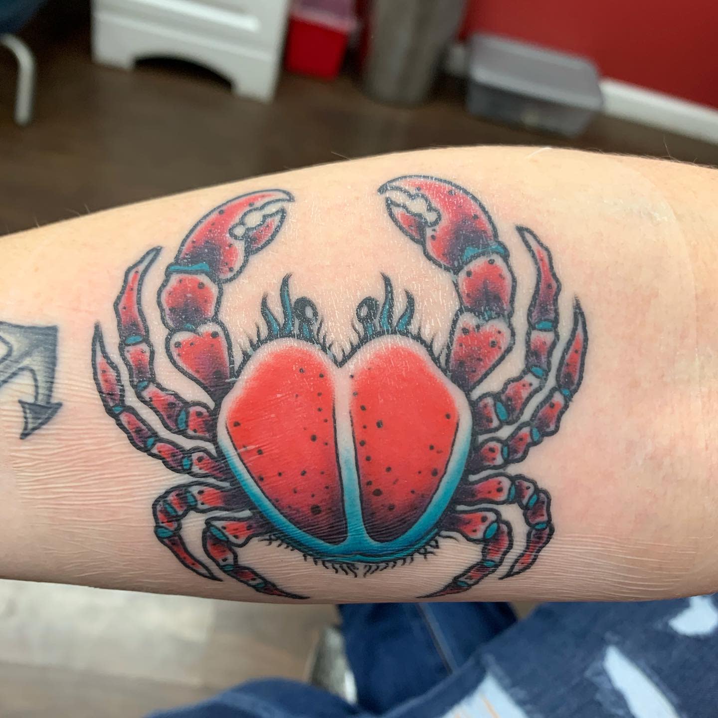Colorful crab tattoo with red claws and body, on pale skin