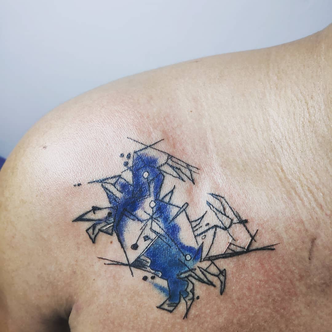 Abstract cancer tattoo on shoulder with blue accents, geometric lines, and dotwork elements