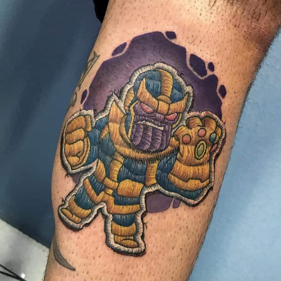 Embroidery-style tattoo of Thanos in a stitched design, featuring his golden armor, Infinity Gauntlet, and a textured patch effect.