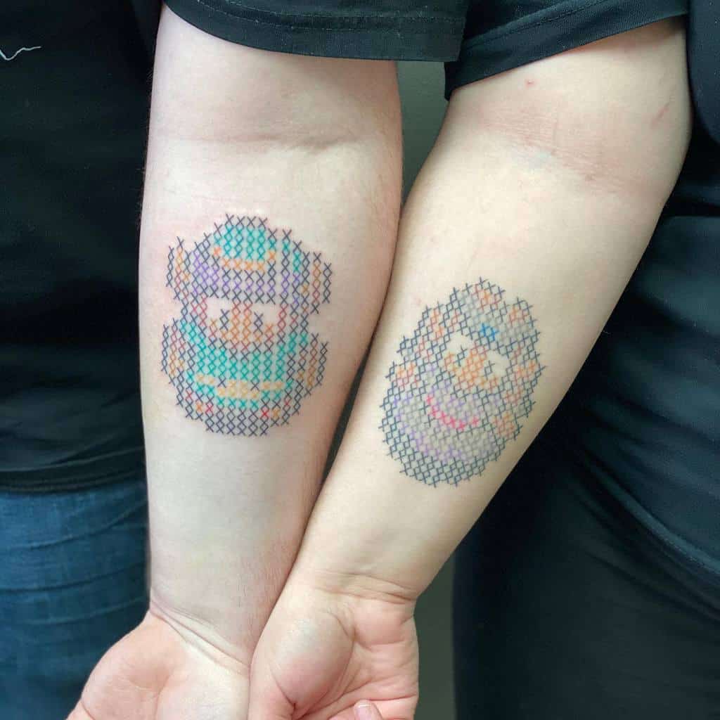 Matching cross-stitch style tattoos of Bub and Bob from Bubble Bobble, blending retro gaming nostalgia