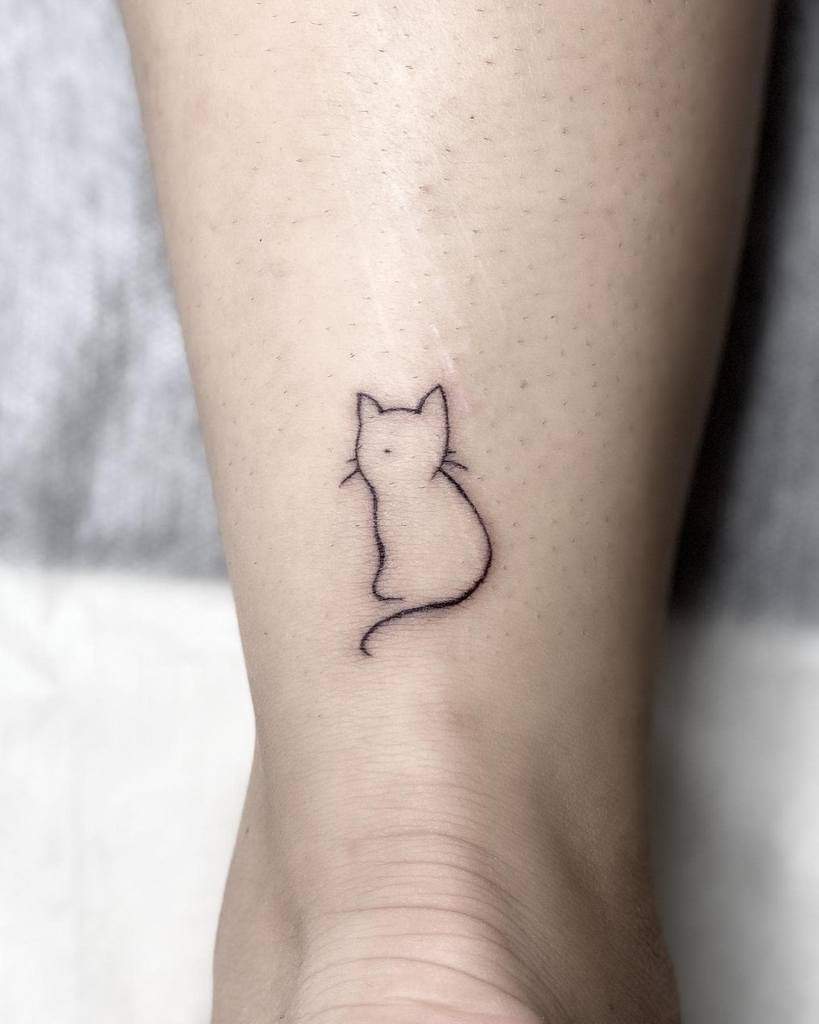 Minimalist outline tattoo of the back of a cat above the ankle