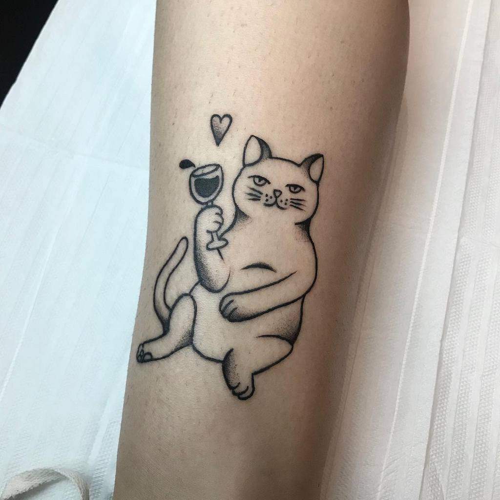 Tattoo of a cat holding a wine glass with a heart above it