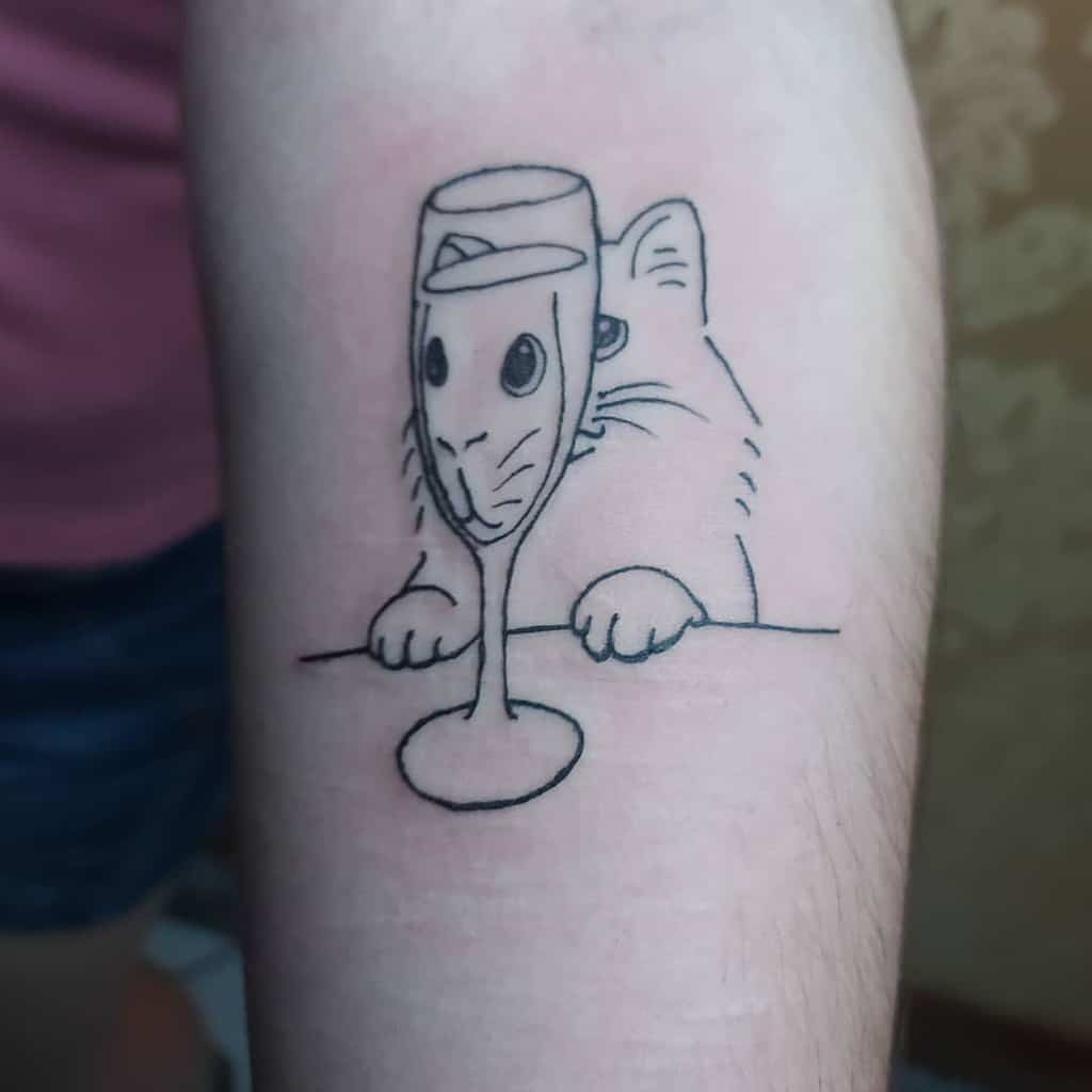 Tattoo of a cat peeking over a surface, its curious face delightfully distorted by a wine glass