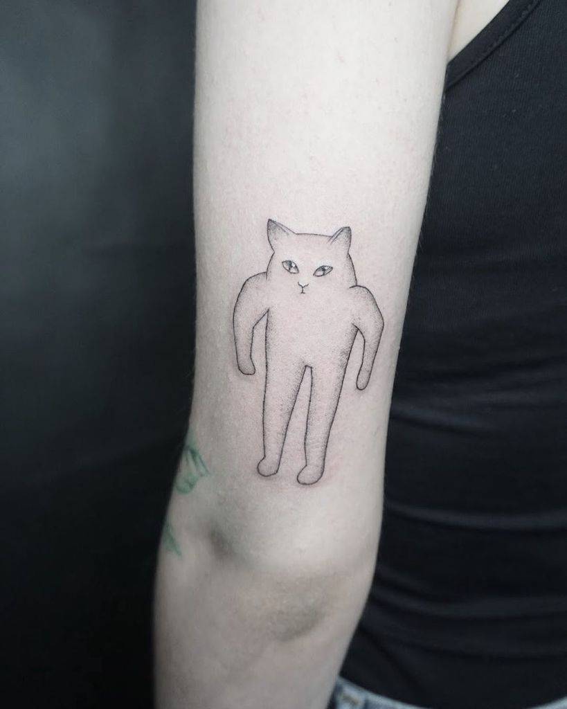 A tattoo of a playful, cartoonish cat on a person's upper arm