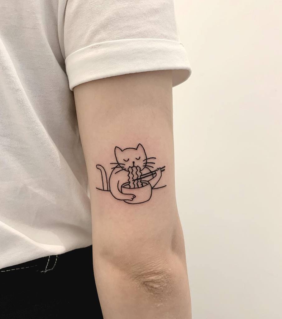 Tattoo of a playful cat enjoying noodles located on the back of a person's upper arm
