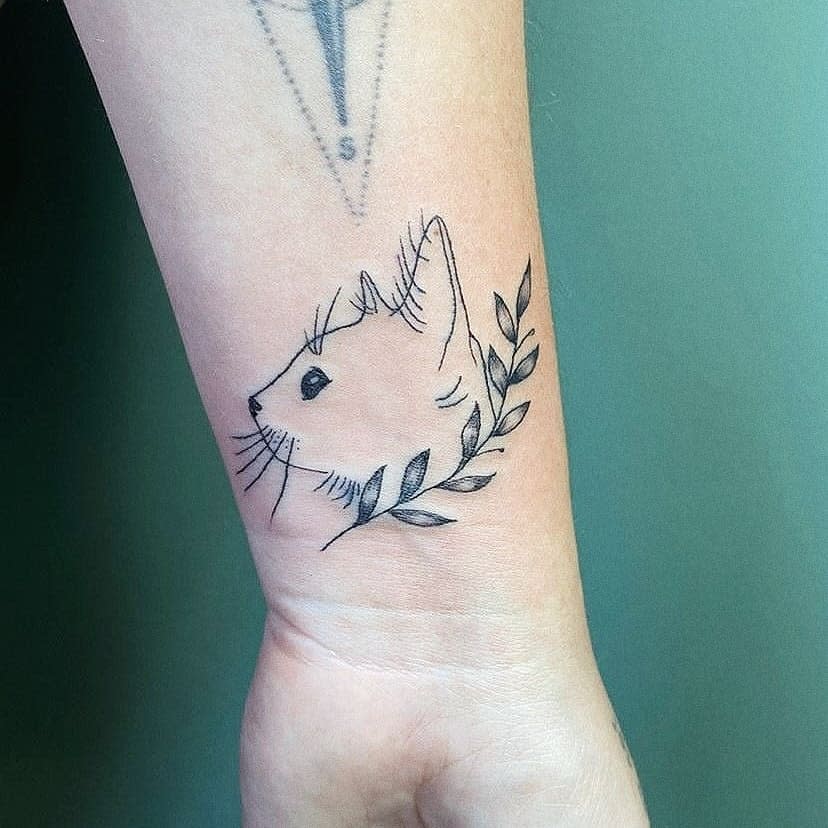 Tattoo of a cat's outline intertwined with delicate leaves on the wrist