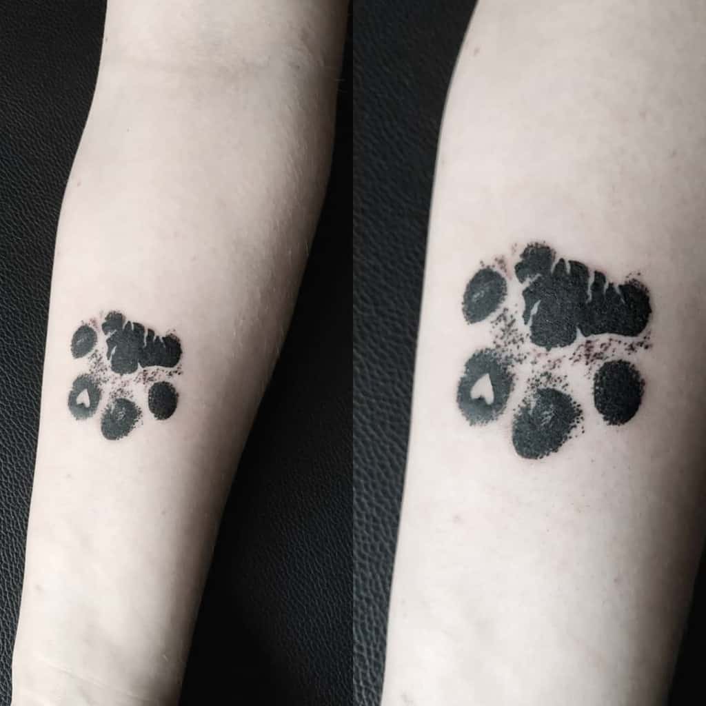Tattoo of a black cat paw print on a person's forearm