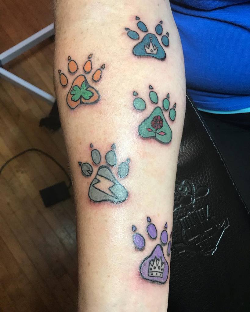 Forearm adorned with vibrant cat paw print tattoos, each showcasing a unique symbol inside