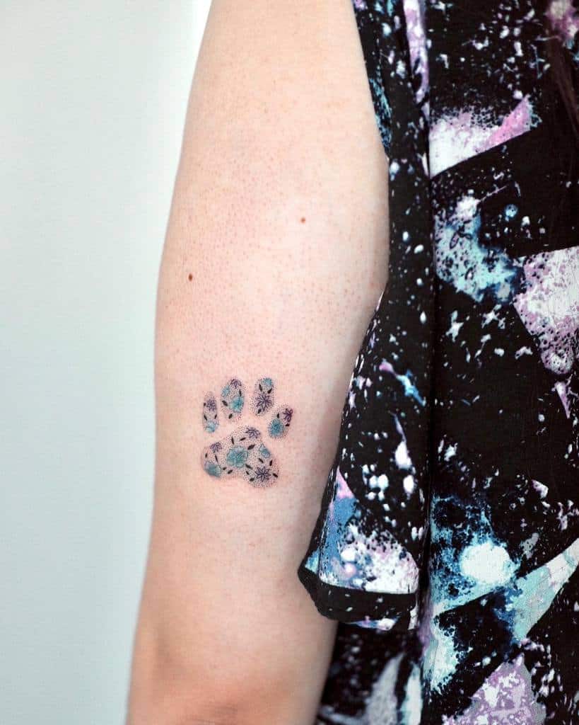 Arm with a cat paw print tattoo with flowers inside it