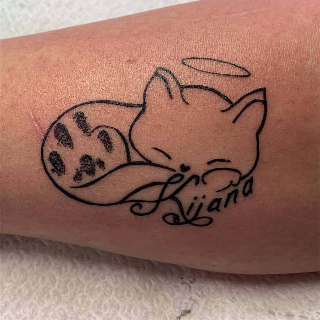 Tattoo of a sleeping angel cat with a cat paw print and banner reading "Kijana"