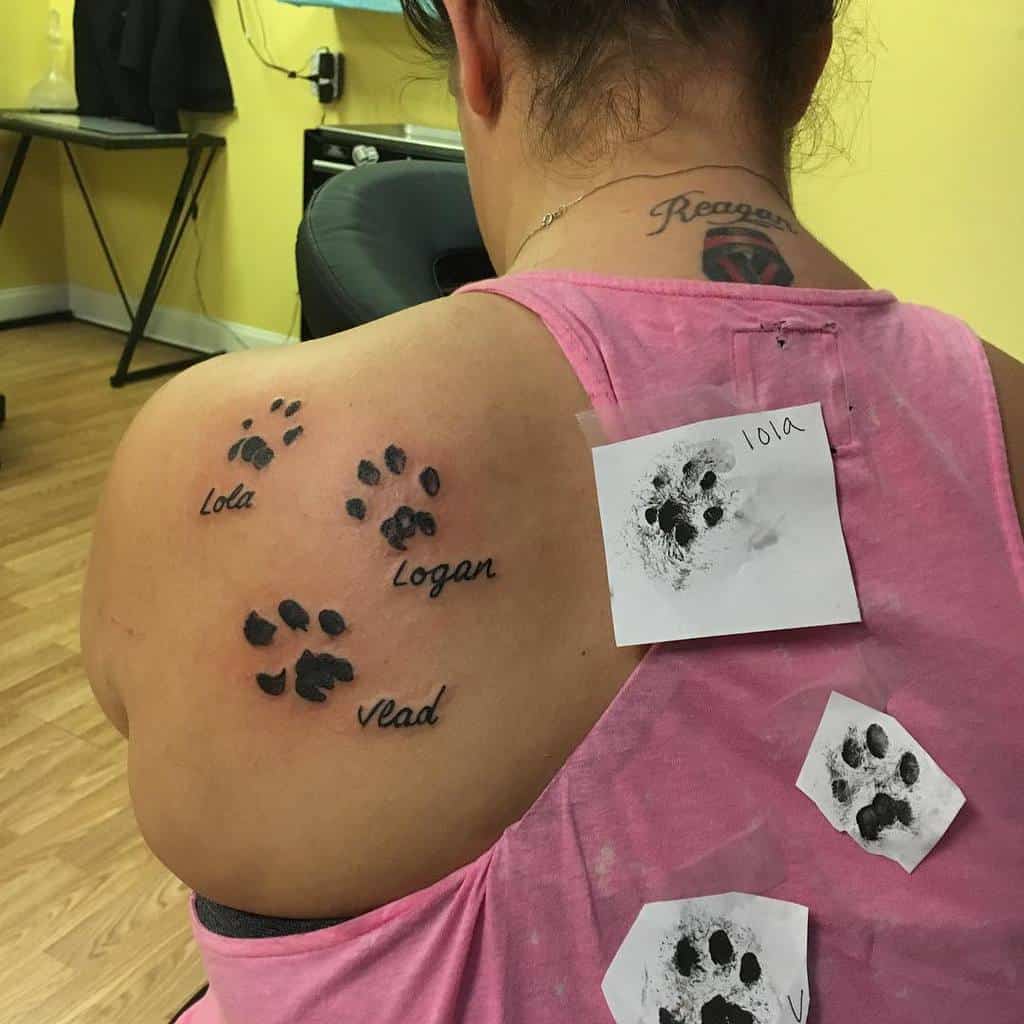 Person with multiple cat paw tattoos and names on their upper back and shoulder