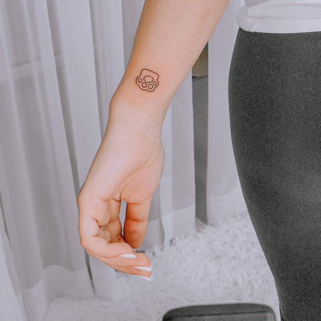 Lower arm with a small outline tattoo of a cat paw print near the wrist